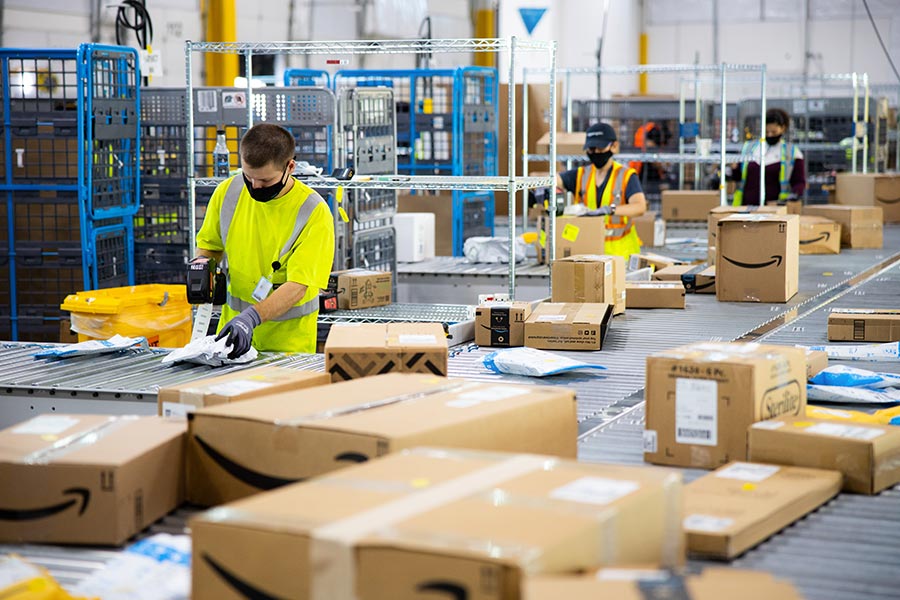 Amazon FBA fulfillment center workers sorting packages on conveyor belt